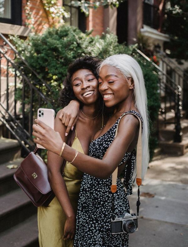 Two friends hugging and taking a selfie, shown as a swipe card