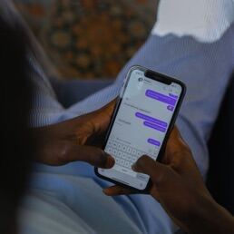 A hand holding a phone showing a chat